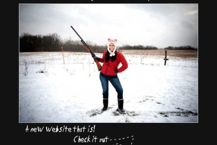 Girl standing in snowy field, smiling while holding shotgun pointed at sky
