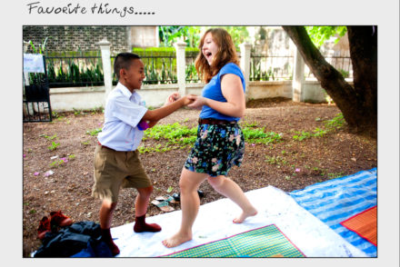 A girl and a young boy dance in a front yard